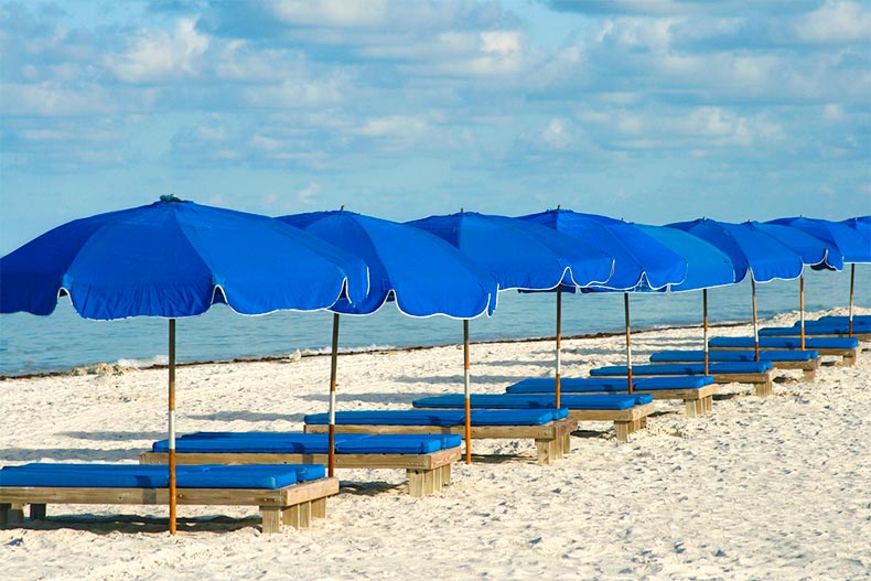 Lounge chairs with umbrellas on Florida beach under blue sky