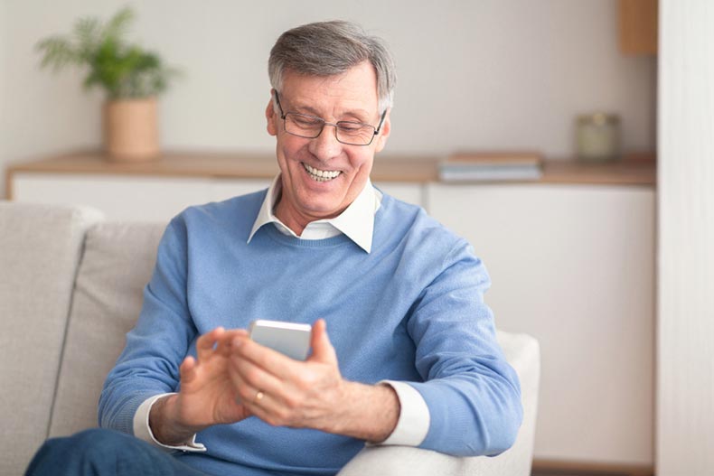 Senior man smiling while playing games on his smart phone