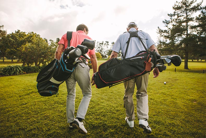 Two men walking with golf bags on a course