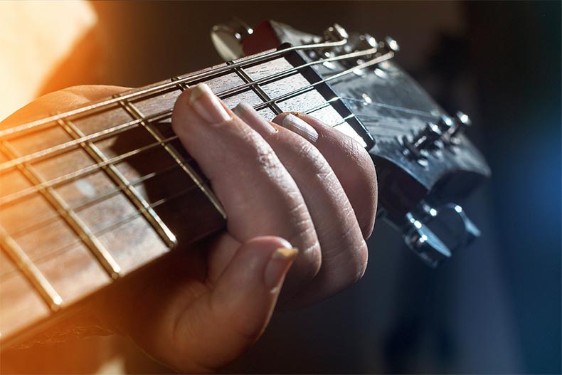 Closeup on a hand pressing on the frets of a guitar