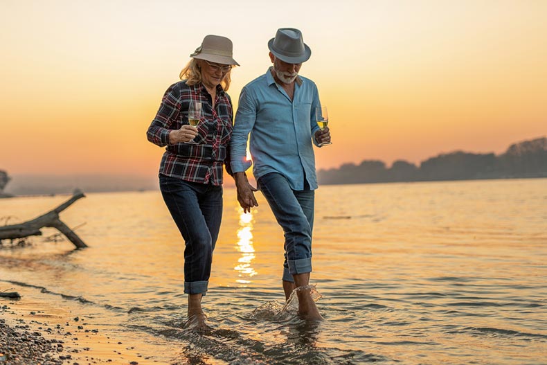 A happy senior couple drinking wine and enjoying the sunset on the river