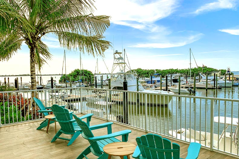 View of a patio with blue lawn chairs over looking a marina with docked yachts