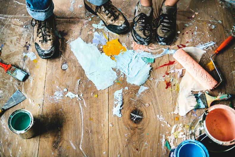 Paint splattered around the feet of people renovating a house
