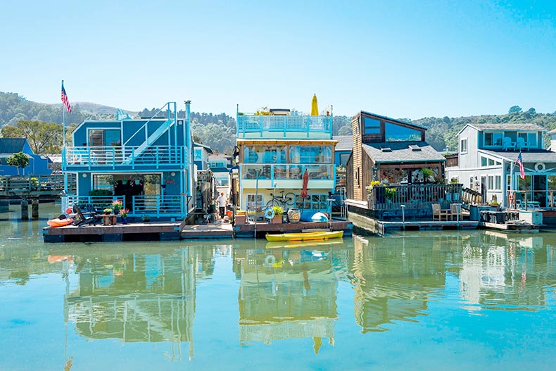 A blue sky over three contemporary houses boats sitting on calm water