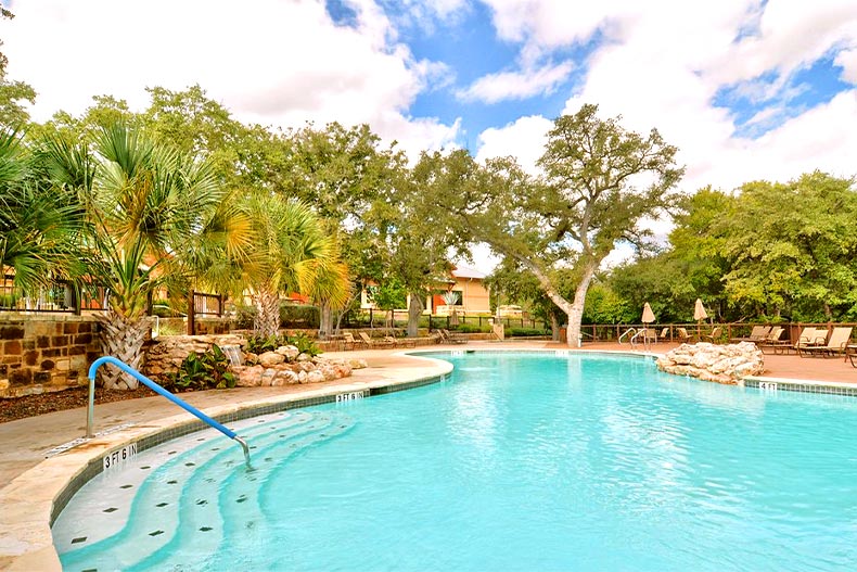 Photo of the outdoor pool at Hill Country Retreat surrounding by palm trees in San Antonio, Texas