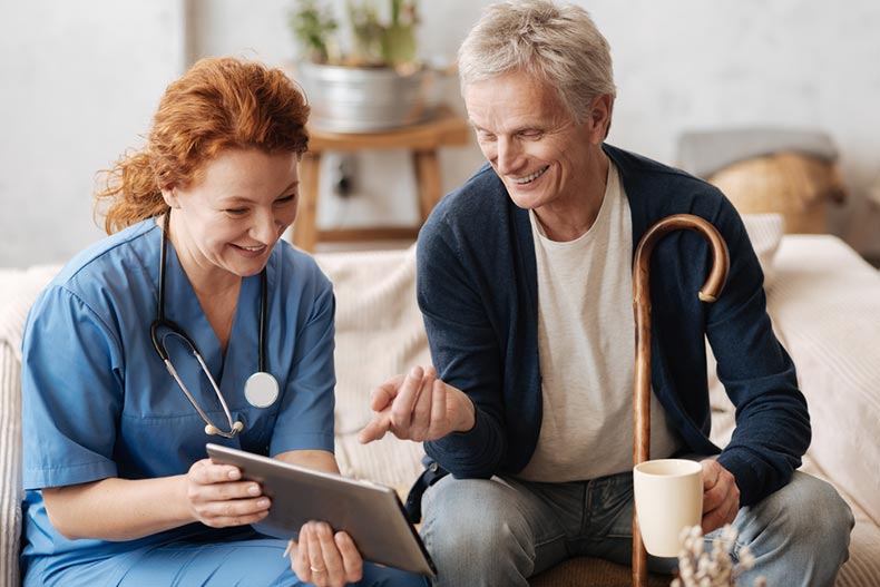 A doctor making a house call to a senior patient and displaying his test results on a tablet