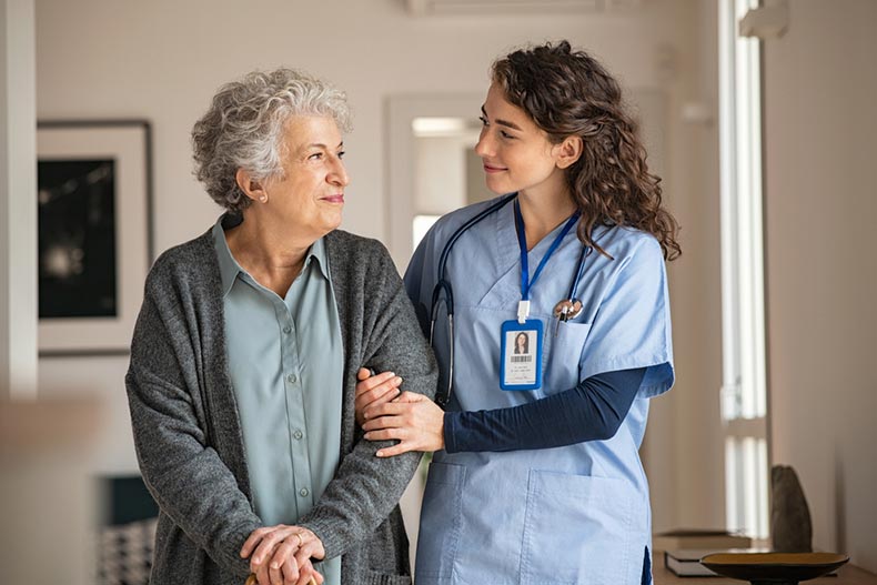A young caregiver helping a senior woman walk in a nursing community