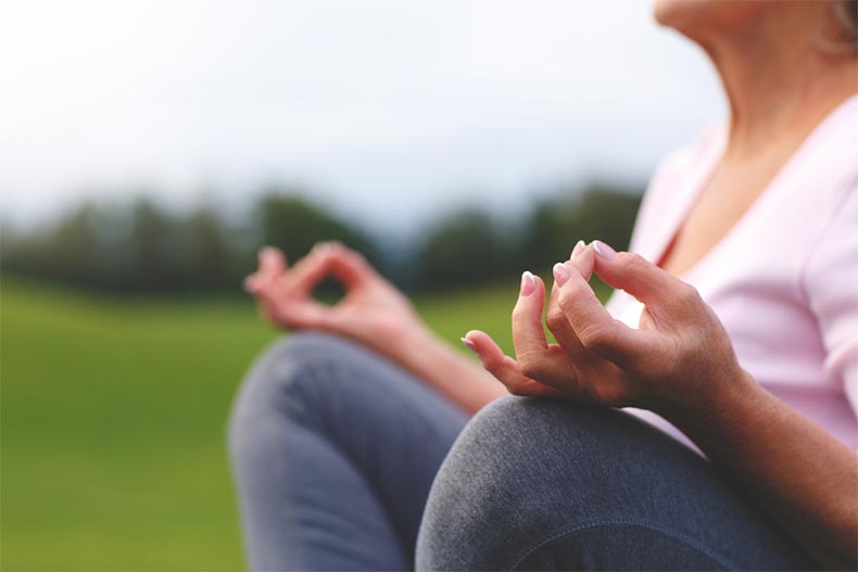 Closeup on the hands of a senior woman as she meditates while practicing yoga