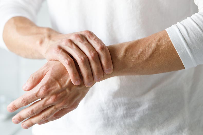Closeup on older male arms holding a pained wrist affected by Arthritis