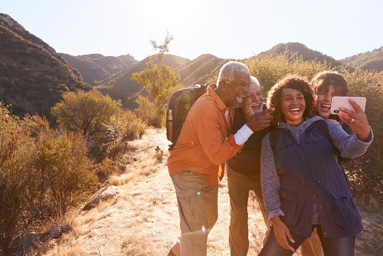 A group of senior friends taking a photo while hiking near their 55+ community