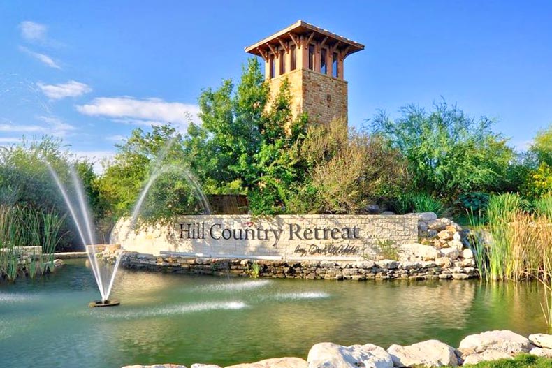 Greenery and a fountain surrounding the community sign for Hill Country Retreat in San Antonio, Texas
