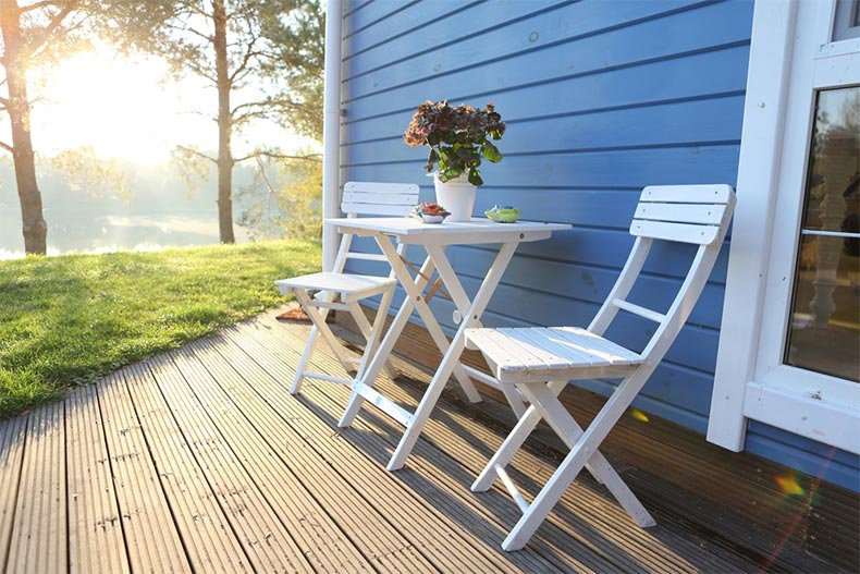 White picnic chairs and a table on a summer terrace outside of a vacation home
