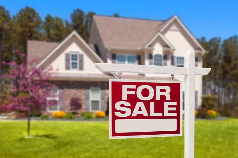 Photo of a for sale sign with a home in the background