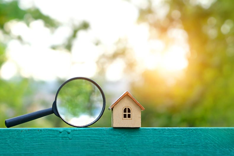 A mini wooden house beside a magnifying glass