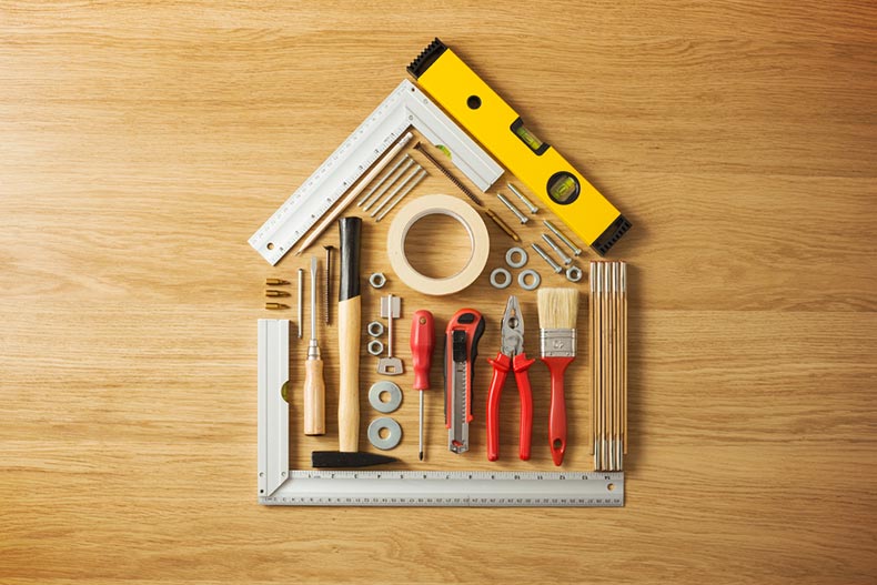 Conceptual house composed of DIY and construction tools on hardwood flooring