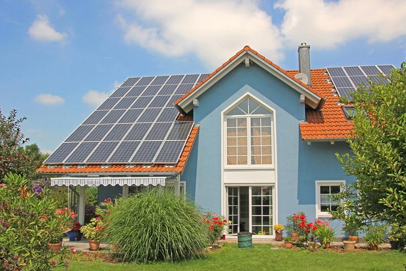 Exterior view of a modern house with a garden and rooftop solar panels