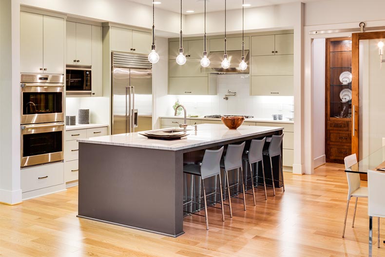 A well-lit kitchen with an island, a sink, cabinets, and hardwood floors