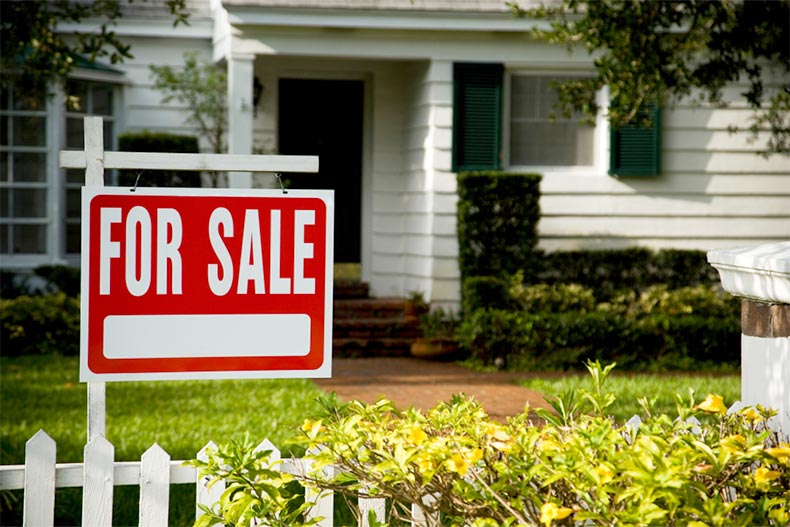 A "For Sale" sign outside of a single-family house