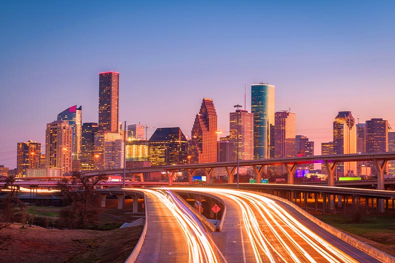 Long-exposure car headlights leading to the Houston, Texas skyline at sunset