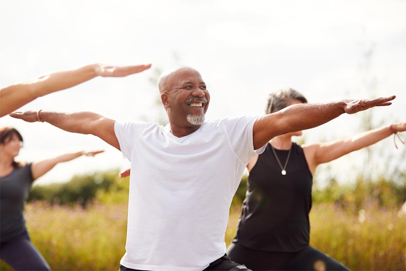 A group of active adults participating in a yoga class outside