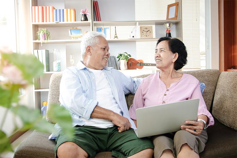 A senior couple sitting on a sofa while looking over their Social Security benefits online