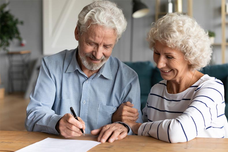 A retired couple signing a document bequeathing their property to their children