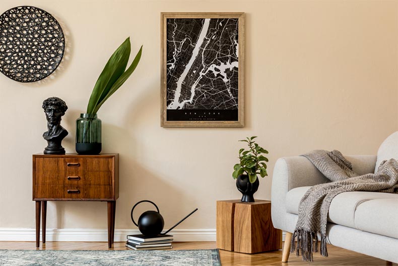 A living room with a poster map, a sofa, flowers in a vase, and elegant personal accessories
