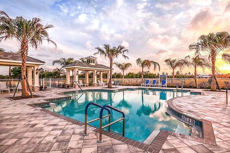 Sunset view of the palm trees and lounge chairs surrounding the outdoor pool at Kings Gate in Port Charlotte, Florida