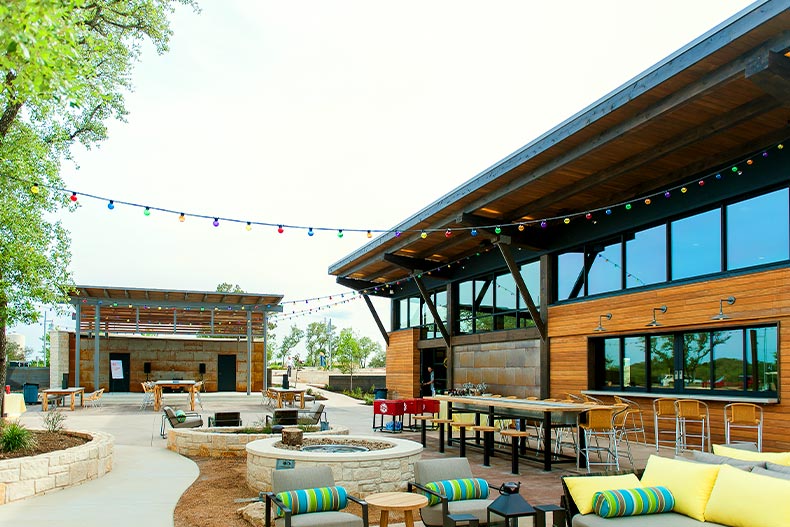 View of the back patio of a clubhouse in Kissing Tree with seating, a fire pit, and a stage, located in San Marcos, Texas