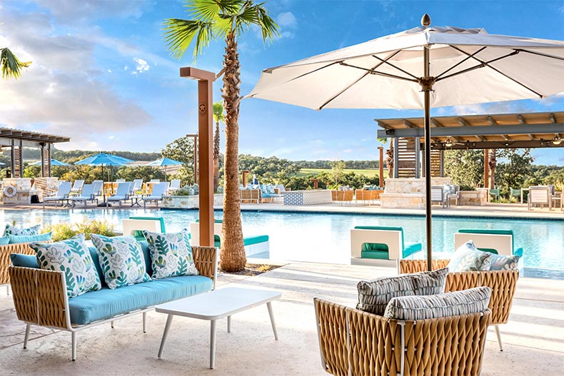 Lounge chairs on the patio beside the outdoor pool at Kissing Tree in San Marcos, Texas