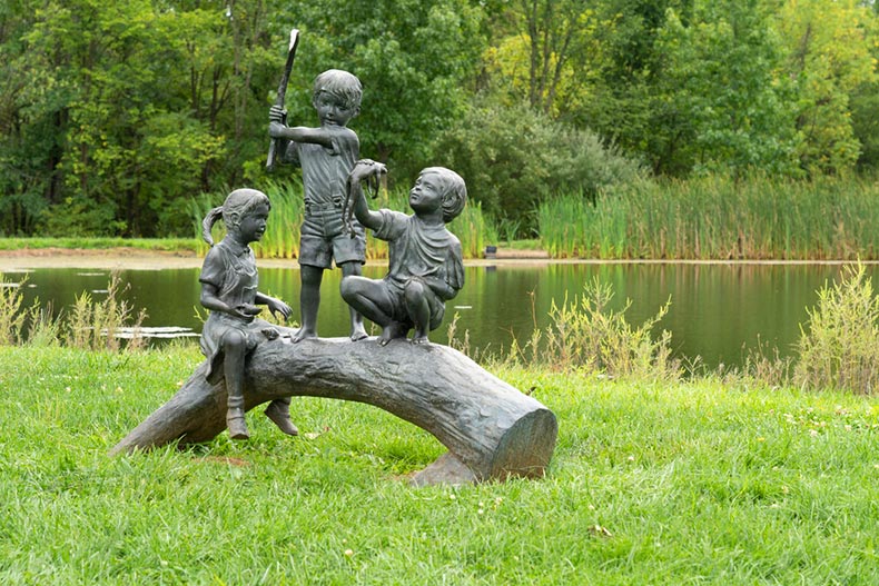 A sculpture of three children on a log in Stony Creek Park in Lansdale, Pennsylvania