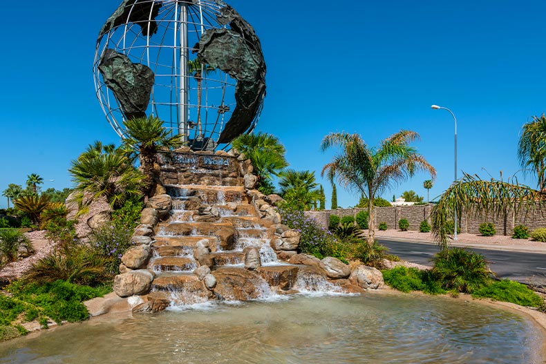 A giant globe over a stone waterfall surrounded by greenery in the Leisure World community of Mesa, Arizona