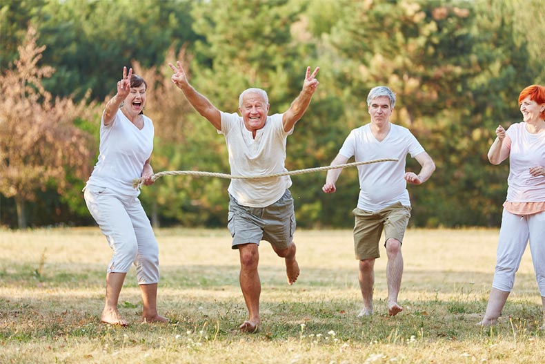 A group of seniors laughing and having fun while running a race barefoot in a park