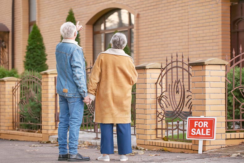 Senior couple with their backs to the camera looking at a home for sale