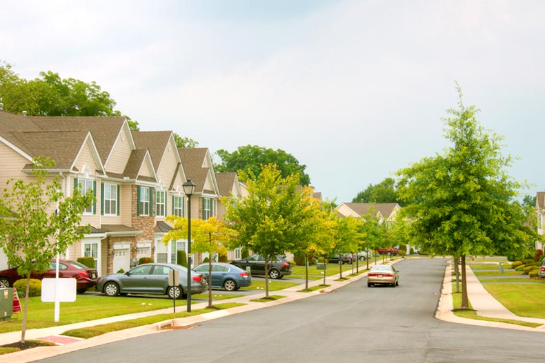 View of a residential street lined with attached homes and trees located in The Village at Maidencreek, Blandon, Pennsylvania