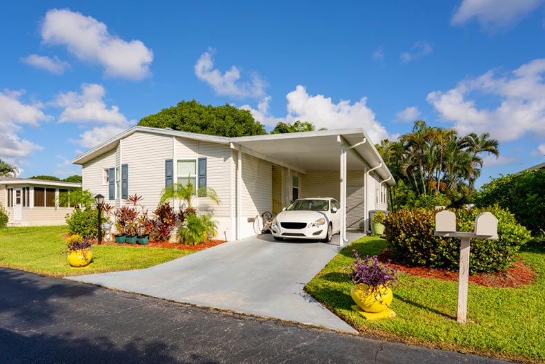 A mobile home in a trailer park with car in driveway