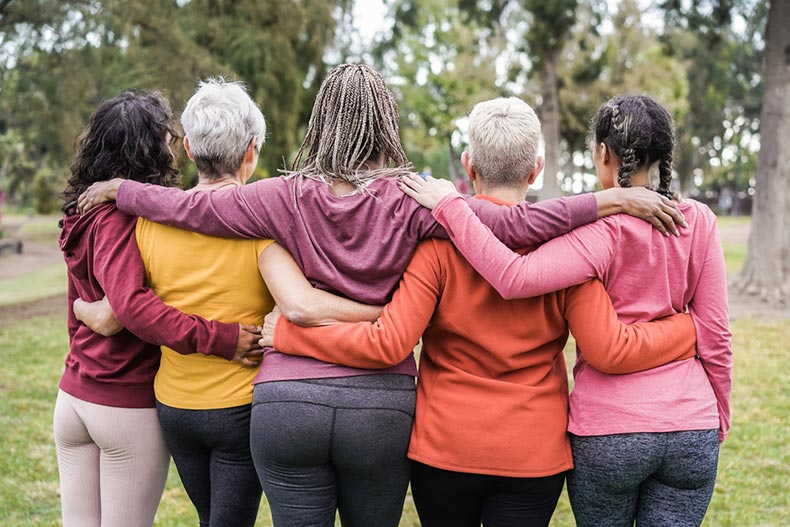 Rear view of a mature group of female friends in exercise clothes with their arms around each other