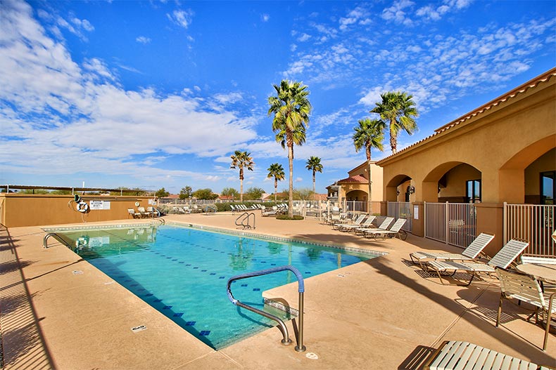 Lounge chairs on the patio beside the outdoor pool at Mission Royale in Casa Grande, Arizona