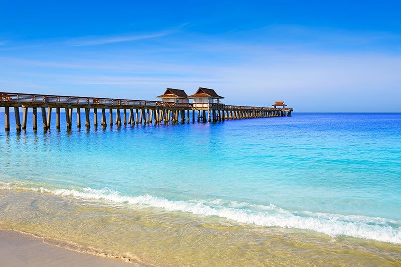 Naples Pier and beach in Florida on sunny day.