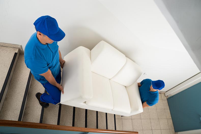 Two movers carrying a sofa down a flight of stairs