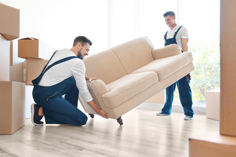 Delivery men moving a sofa into a new home