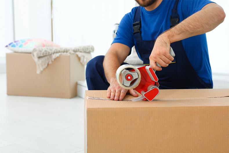 A man using tape to seal up moving boxes