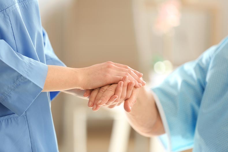 A young doctor holding the hand of an elderly woman in a hospital