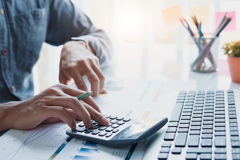 Close up on hands holding a pencil and working on a calculator to calculate taxes