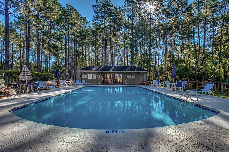 Exterior of the pool and patio at Myrtle Trace with trees surrounding the background.