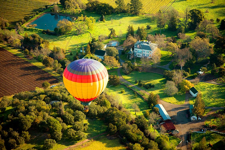 Aerial view of a Napa Valley vineyard and farm with a hot air balloon flying overhead