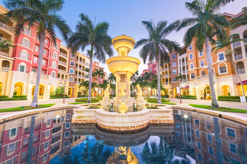 A fountain surrounded by palm trees in Naples, Florida at twilight