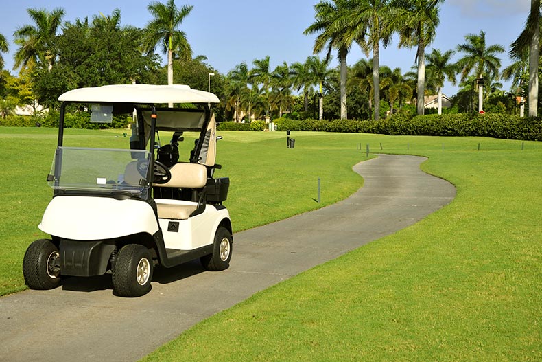 An empty golf cart parked on a pathway on a golf course in Naples, Florida