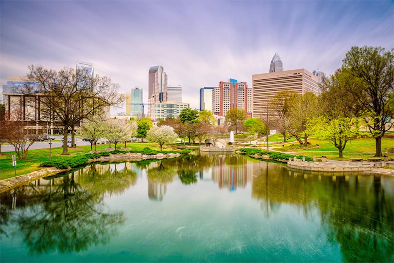 View of a pond and green landscaping with the skyline of Charlotte, North Carolina in the background