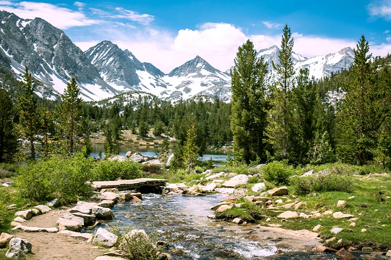 View of a creek in Sierra, Nevada with snow-capped California mountains in the background.